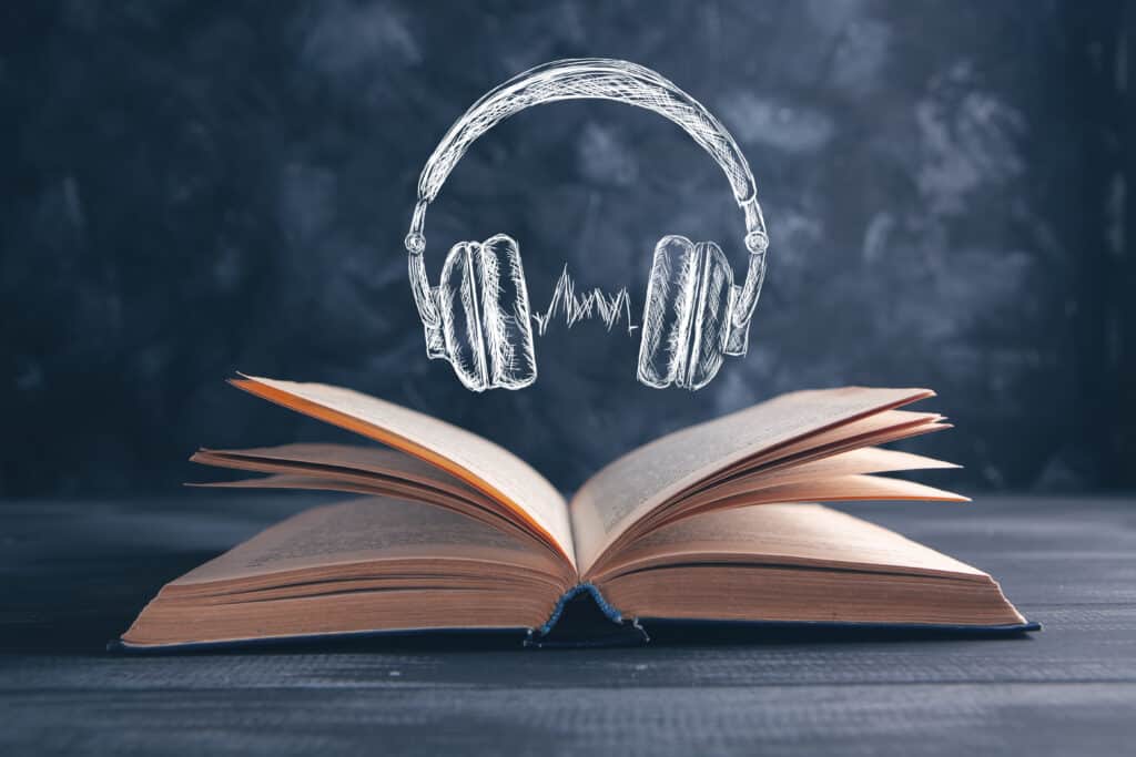 chalk drawing of headphones over open real book on table top with chalkboard background to show listening and reading comprehension relationship