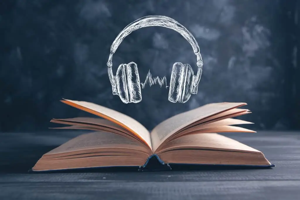 chalk drawing of headphones over open real book on table top with chalkboard background to show listening and reading comprehension relationship