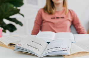 A young female students sitting in a desk chair looking over texts for syntax and comprehension blog image